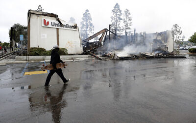 A man passes a burning bank building after a protest over the death of George Floyd, Sunday, May 31, 2020, in La Mesa, Calif. (AP/Gregory Bull)
