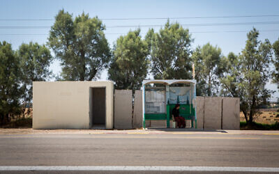 Illustrative: A woman waits at a bus stop near a public bomb shelter, by the southern kibbutz of Kfar Aza on July 06, 2015. (Miriam Alster/FLASH90)