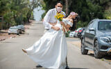 Illustrative: Gal Sade Knigsfild and Nofar Almakias pose for a picture with face masks before their wedding in Moshav Yashresh on April 6, 2020 (Yossi Aloni/Flash90)