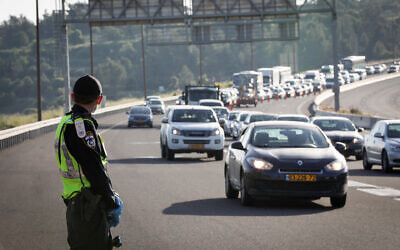 A police officer stands guard at a roadblock on a road leading to Ein Hemed, near Jerusalem, on April 28, 2020 (Nati Shohat/Flash90)