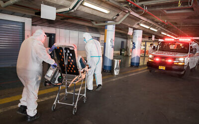 Medical personel in protective gear bring a patient suspected of having the coronavirus to Shaare Zedek Medical Center in Jerusalem on April 30, 2020. (Nati Shohat/Flash90)