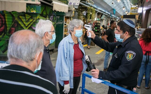 People have their temperature checked at they enter the Mahane Yehuda market in Jerusalem after it reopened according to the new government orders, May 7, 2020. (Olivier Fitoussi/Flash90)