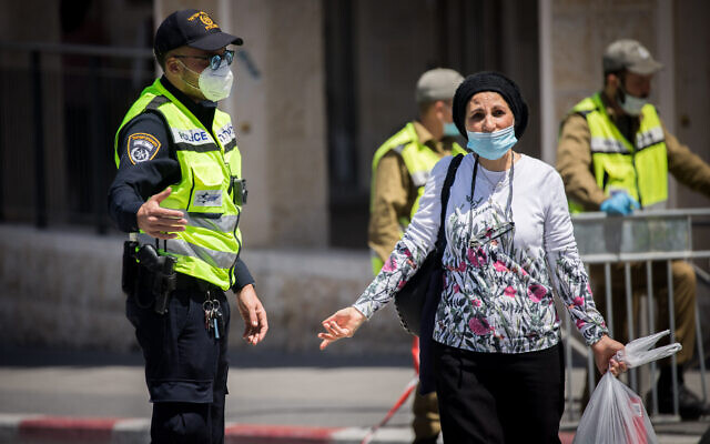 A woman speaks with a police officer at a roadblock in the Jerusalem neighborhood of Romema, which is under a lockdown to prevent the spread of the coronavirus, May 4, 2020. (Yonatan Sindel/Flash90) A woman speaks with a police officer at a roadblock in the Jerusalem neighborhood of Romema, which is under a lockdown to prevent the spread of the coronavirus, May 4, 2020. (Yonatan Sindel/Flash90)