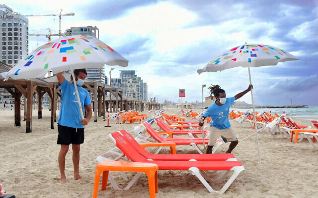 Workers arrange beach chairs and umbrellas at the Tel Aviv beach on May 5, 2020. (Avshalom Sassoni/Flash90) Workers arrange beach chairs and umbrellas at the Tel Aviv beach on May 5, 2020. (Avshalom Sassoni/Flash90)