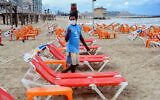 Workers arrange beach chairs and umbrellas at the Tel Aviv beach, May 5, 2020. (Avshalom Sassoni/Flash90)