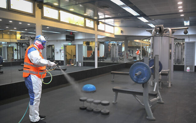 A worker wearing protective clothing disinfects a gym at the Tel Aviv University Sports Center, May 6, 2020. (Flash90)