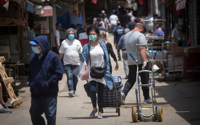 People wear protective face masks as they shop at the Carmel market in Tel Aviv before it officially opens up to the public, May 6, 2020. (Miriam Alster/FLASH90)