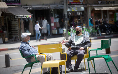 People wear protective face masks as they shop at the Carmel market in Tel Aviv before it officially opens up to the public, May 6, 2020. (Miriam Alster/FLASH90)