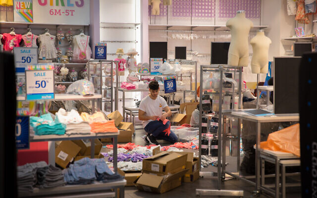 Staff members wearing face masks and gloves prepare their stores for reopening at the Hadar Shopping mall in Jerusalem, May 6, 2020. (Olivier Fitoussi/FLASH90)