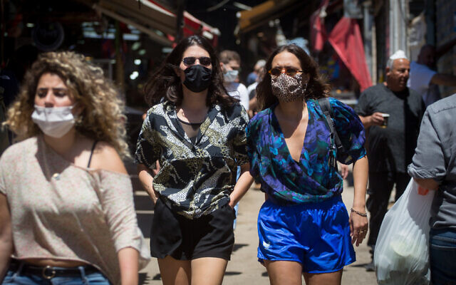 People wear protective face masks as they shop at the Carmel market in Tel Aviv, May 8, 2020. (Miriam Alster/FLASH90) People wear protective face masks as they shop at the Carmel market in Tel Aviv, May 8, 2020. (Miriam Alster/FLASH90)