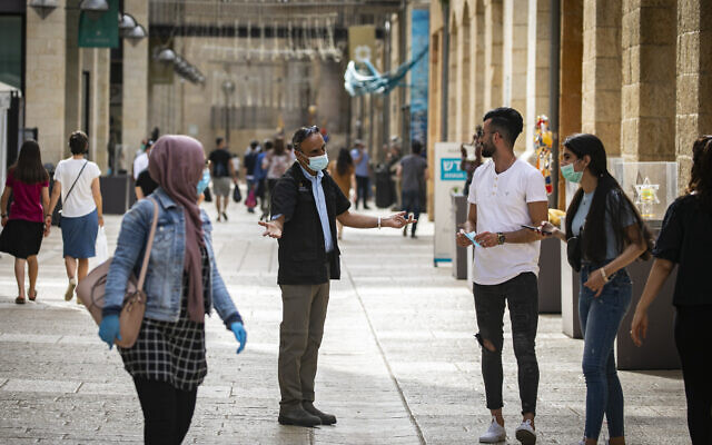 A security guard asks people to put on face masks at the Mamilla Mall near Jerusalem's Old City, on May 14, 2020. (Olivier Fitoussi/Flash90) A security guard asks people to put on face masks at the Mamilla Mall near Jerusalem's Old City, on May 14, 2020. (Olivier Fitoussi/Flash90)