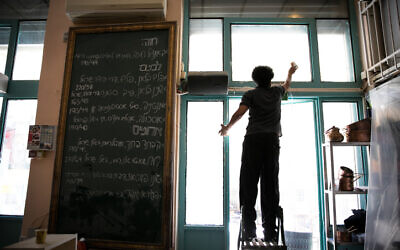 Staff members clean prior to the reopenning of the Machneyuda restaurant in Jerusalem on May 25, 2020. (Olivier Fitoussi/Flash90)