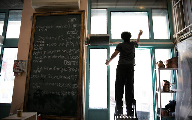 Staff members clean prior to the reopenning of the Machneyuda restaurant in Jerusalem on May 25, 2020. (Olivier Fitoussi/Flash90) Staff members clean prior to the reopenning of the Machneyuda restaurant in Jerusalem on May 25, 2020. (Olivier Fitoussi/Flash90)