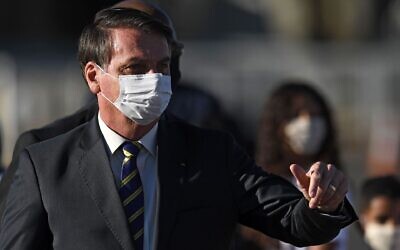 Brazilian President Jair Bolsonaro, wearing a face mask, gestures as he speaks to supporters while arriving at a ministerial meeting at the Alvorada Palace in Brasilia, Brazil, May 12, 2020. (Evaristo Sa/AFP via Getty Images)