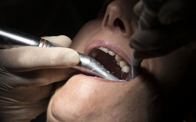 Illustrative: A dentist wearing protective equipment treats a patient in Guebwiller, eastern France, May 20, 2020. (Sebastien Bozon/AFP) Illustrative: A dentist wearing protective equipment treats a patient in Guebwiller, eastern France, May 20, 2020. (Sebastien Bozon/AFP)