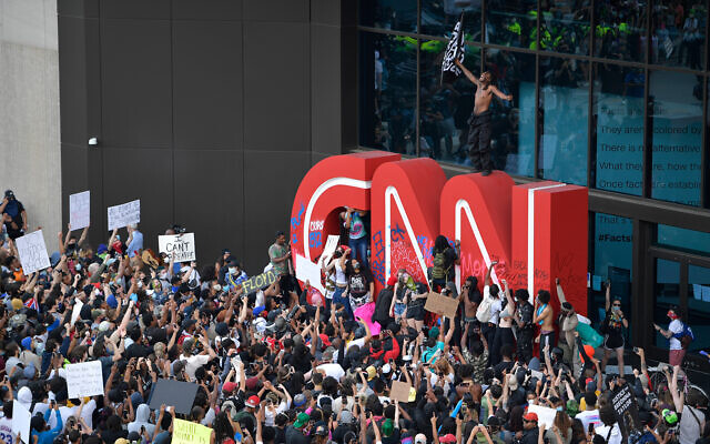 Demonstrators paint on the CNN logo during a protest march over George Floyd's death in Atlanta, Georgia, May 29, 2020. (AP/Mike Stewart)