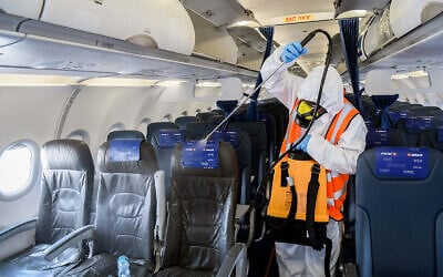 A worker disinfects a Israir plane at Ben-Gurion International Airport near Tel Aviv, May 5, 2020. (Yossi Zeliger/Flash90) A worker disinfects a Israir plane at Ben-Gurion International Airport near Tel Aviv, May 5, 2020. (Yossi Zeliger/Flash90)