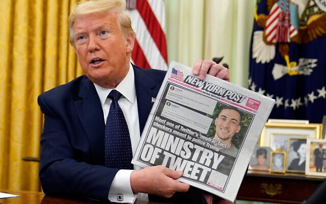 US President Donald Trump holds up a copy of the New York Post before signing an executive order aimed at curbing protections for social media giants, the White House, May 28, 2020. (AP/Evan Vucci) US President Donald Trump holds up a copy of the New York Post before signing an executive order aimed at curbing protections for social media giants, the White House, May 28, 2020. (AP/Evan Vucci)