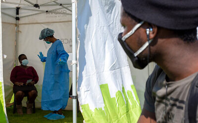 A man looks through a tent opening as a heath worker explains the process of collecting a sample for coronavirus testing near Johannesburg, South Africa, May 8, 2020. (AP/Themba Hadebe)