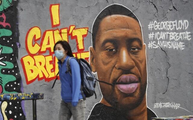 A woman wearing a protective mask walks past graffiti in Berlin's Mauer Park depicting George Floyd, a black man who died in Minneapolis after a white policeman kneeled on his neck for several minutes. (Photo by Odd ANDERSEN / AFP) A woman wearing a protective mask walks past graffiti in Berlin's Mauer Park depicting George Floyd, a black man who died in Minneapolis after a white policeman kneeled on his neck for several minutes. (Photo by Odd ANDERSEN / AFP)