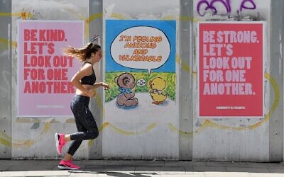 A woman runs to exercise past posters promoting community spirit, erected during the novel coronavirus COVID-19 pandemic, in Manchester, northern England on June 2, 2020. (Paul ELLIS / AFP)
