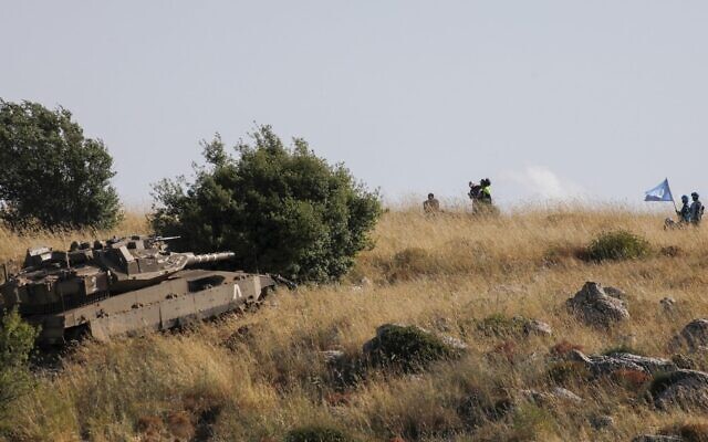In this photo taken near Kibbutz Misgav Am, Lebanese soldiers and UNIFIL peacekeepers watch from the southern Lebanese village of Adaisseh as an IDF Merkava tank takes part in routine maneuvers near the border demarcation line, June 2, 2020. (Jalaa Marey/AFP) In this photo taken near Kibbutz Misgav Am, Lebanese soldiers and UNIFIL peacekeepers watch from the southern Lebanese village of Adaisseh as an IDF Merkava tank takes part in routine maneuvers near the border demarcation line, June 2, 2020. (Jalaa Marey/AFP)