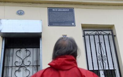 A man looks at a street plaque on the rue Gramont in Bordeaux, on June 11, 2020, set up as part of new explanatory versions of street plaques bearing the names of city historical figures who took part in slave trade. (NICOLAS TUCAT / AFP)