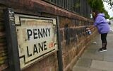 A local resident cleans graffiti from a wall on Penny Lane in Liverpool, north west England on June 12, 2020, after a wall and street signs were defaced (Oli SCARFF / AFP)