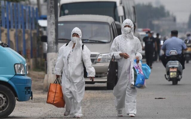 Two women wear protective suits as they walk on a street near the closed Xinfadi market in Beijing on June 13, 2020. (GREG BAKER / AFP) Two women wear protective suits as they walk on a street near the closed Xinfadi market in Beijing on June 13, 2020. (GREG BAKER / AFP)