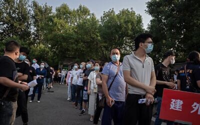 A group of people wearing face masks wait in a queue to undergo COVID-19 coronavirus tests in Beijing on June 19, 2020 (NICOLAS ASFOURI / AFP)
