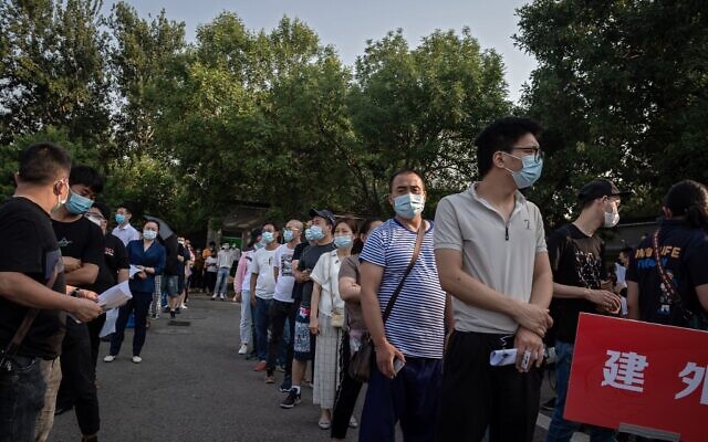 A group of people wearing face masks wait in a queue to undergo COVID-19 coronavirus tests in Beijing on June 19, 2020 (NICOLAS ASFOURI / AFP)