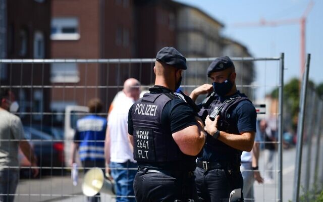 Police officers stand guard near the residential homes of the employees of Toennies abatoir, in Verl, western Germany on June 23, 2020, amid the novel coronavirus pandemic. (FASSBENDER/AFP) Police officers stand guard near the residential homes of the employees of Toennies abatoir, in Verl, western Germany on June 23, 2020, amid the novel coronavirus pandemic. (FASSBENDER/AFP)
