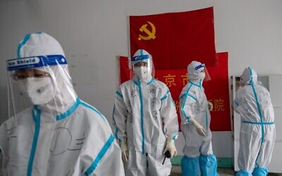 Illustrative: Medics from Beijing Fengsheng Special Hospital of Traditional Medical Traumatology and Orthopaedics prepare for their shift at the Jinrong Street testing site, inside a room where a Communist Party flag and a piece of red tissue with words that reads "Beijing Fengsheng Special Hospital of Traditional Medical Traumatology and Orthopaedics" (back on wall) in Beijing on June 24, 2020. (NICOLAS ASFOURI / AFP)