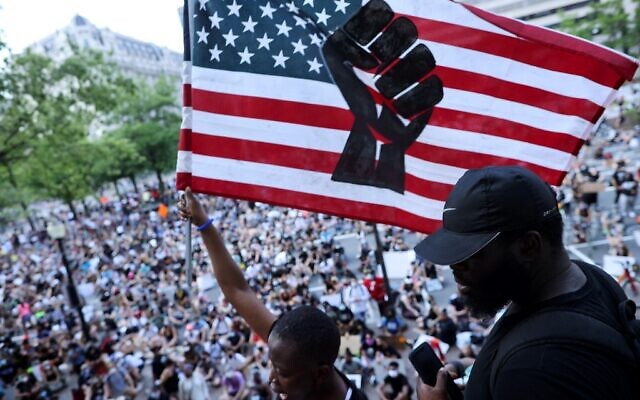 Pilomena Wankenge of the DC Freedom Fighters waves an American flag to a crowd gathered at the John A. Wilson Building during a protest against police brutality and racism on June 6, 2020 in Washington, DC. (Chip Somodevilla/Getty Images/AFP) Pilomena Wankenge of the DC Freedom Fighters waves an American flag to a crowd gathered at the John A. Wilson Building during a protest against police brutality and racism on June 6, 2020 in Washington, DC. (Chip Somodevilla/Getty Images/AFP)