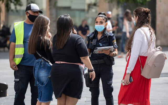 A police officer gives fines to young women for not properly wearing their face masks in the city center of Jerusalem on June 11, 2020. (Olivier Fitoussi/Flash90) A police officer gives fines to young women for not properly wearing their face masks in the city center of Jerusalem on June 11, 2020. (Olivier Fitoussi/Flash90)