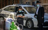 A police officer writes up a fine for a woman who was not wearing a mask in Jerusalem on June 24, 2020. (Olivier Fitoussi/Flash90)