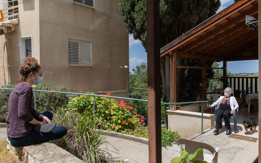 A young woman visits her grandmother in Kibbutz Barkai, Israel, April 26, 2020. (Guy Prives/Getty Images/ via JTA)