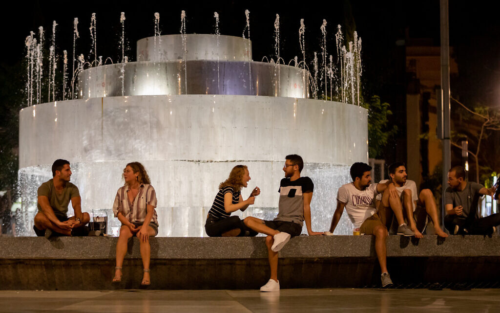 People sit at Dizengoff Square in Tel Aviv with drinks from home and the surrounding bars, May 18, 2020. Lockdown restrictions have been partly removed. (Guy Prives/Getty Images/ via JTA)
