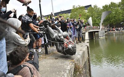 Protesters throw a statue of slave trader Edward Colston into Bristol harbour, during a Black Lives Matter protest rally, in Bristol, England, June 7, 2020. (Ben Birchall/PA via AP)
