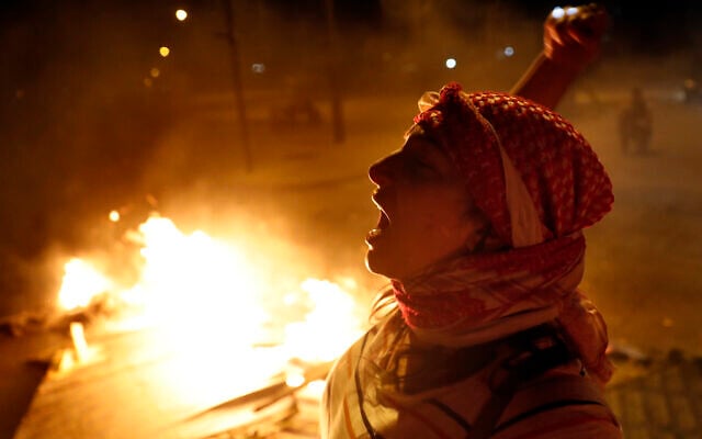 An anti-government protester chants slogans as others burn wood and barriers to block a road during a protest against the political leadership they blame for the economic and financial crisis, in Beirut, Lebanon, June 11, 2020. (AP Photo/Hussein Malla) An anti-government protester chants slogans as others burn wood and barriers to block a road during a protest against the political leadership they blame for the economic and financial crisis, in Beirut, Lebanon, June 11, 2020. (AP Photo/Hussein Malla)