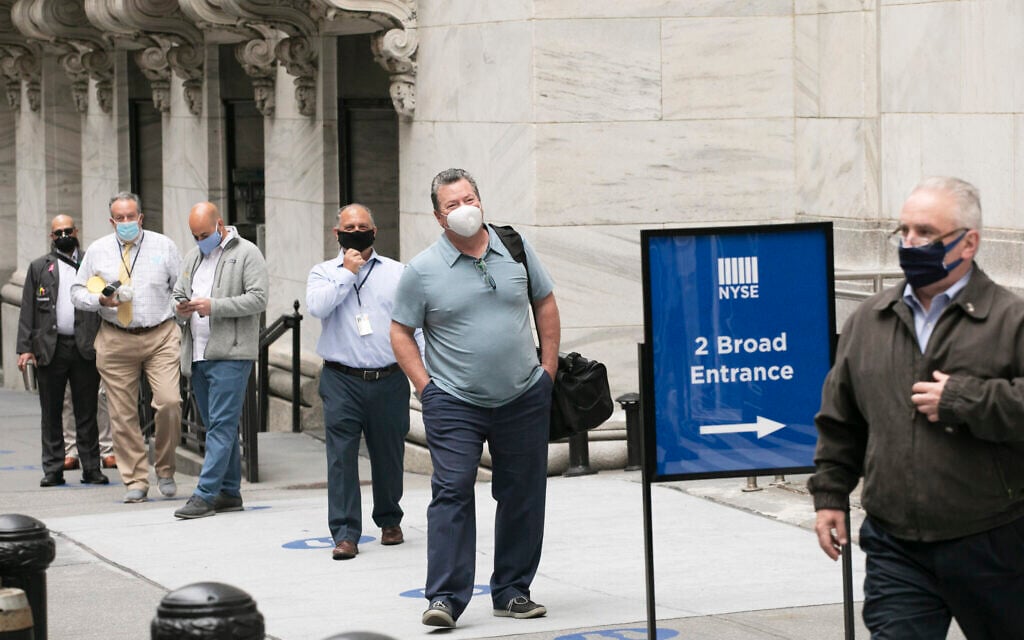 New York Stock Exchange employees wait to enter the building as the trading floor partially reopens, Tuesday, May 26, 2020. (AP Photo/Mark Lennihan)