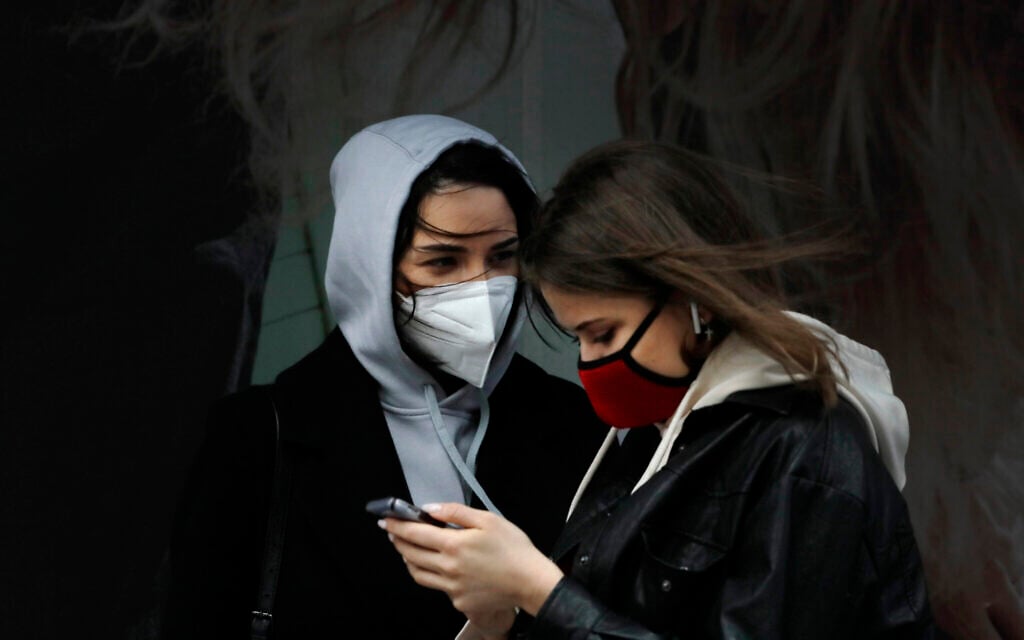 Women wearing masks talk in New York's Times Square, April 9, 2020, during the coronavirus epidemic. (AP Photo/Mark Lennihan)