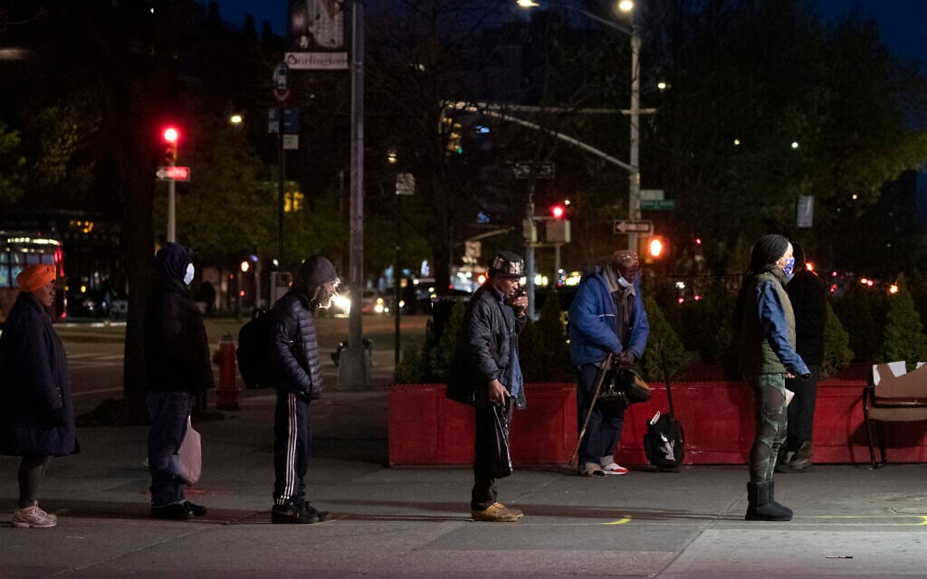 People maintain social distancing while waiting in line to enter a store Thursday, April 16, 2020, in the Harlem neighborhood of New York. (AP Photo/Mark Lennihan)
