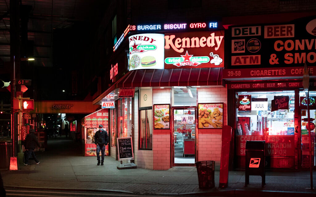 A man walks past an open Kennedy Fried Chicken restaurant in the Queens borough of New York, Thursday night, April 23, 2020, during the coronavirus pandemic. (AP Photo/Mark Lennihan)