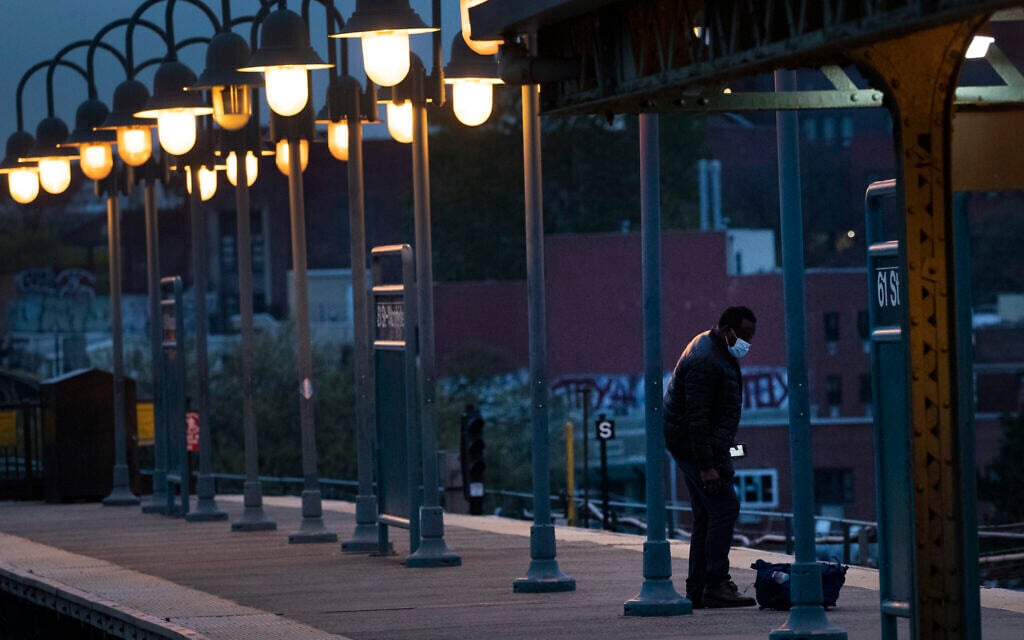 A man waits for a subway in the Woodside neighborhood in the Queens borough of New York, Thursday night, April 23, 2020, during the coronavirus pandemic. (AP Photo/Mark Lennihan)