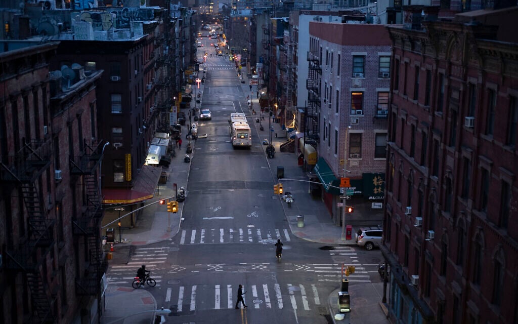 Bicyclists and a pedestrian pass through a quiet Manhattan street, March 26, 2020, during the coronavirus pandemic in New York. (AP Photo/Mark Lennihan)