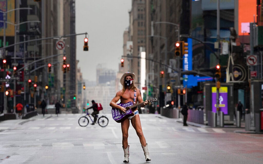 Street performer Robert John Burck, known as The Naked Cowboy, poses for photos in New York's Times Square, Thursday, April 9, 2020, during the coronavirus epidemic. (AP Photo/Mark Lennihan)