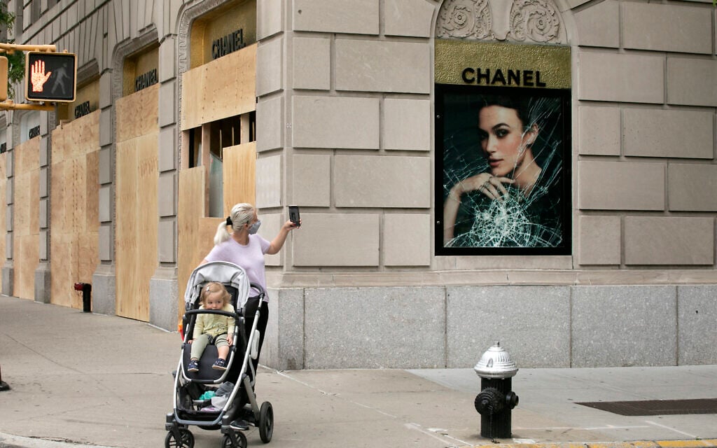 A woman photographs a smashed Chanel store window, Tuesday, June 2, 2020, on Madison Avenue in New York. (AP Photo/Mark Lennihan)