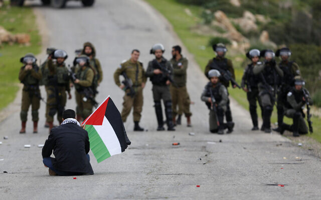 A Palestinian demonstrator holds a Palestinian flag in front of Israeli forces during a protest against US President Donald Trump's peace plan, in the Jordan Valley in the West Bank, on February 25, 2020. (AP Photo/Majdi Mohammed, File) A Palestinian demonstrator holds a Palestinian flag in front of Israeli forces during a protest against US President Donald Trump's peace plan, in the Jordan Valley in the West Bank, on February 25, 2020. (AP Photo/Majdi Mohammed, File)