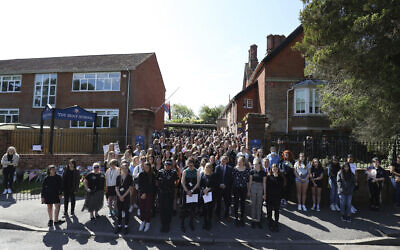 Colleagues and pupils of teacher James Furlong stand together to take part in a period of silence at the Holt School, in Wokingham, England, in memory of teacher James Furlong, a victim of a terror attack in nearby Reading, June 22, 2020. (Steve Parsons/PA via AP)